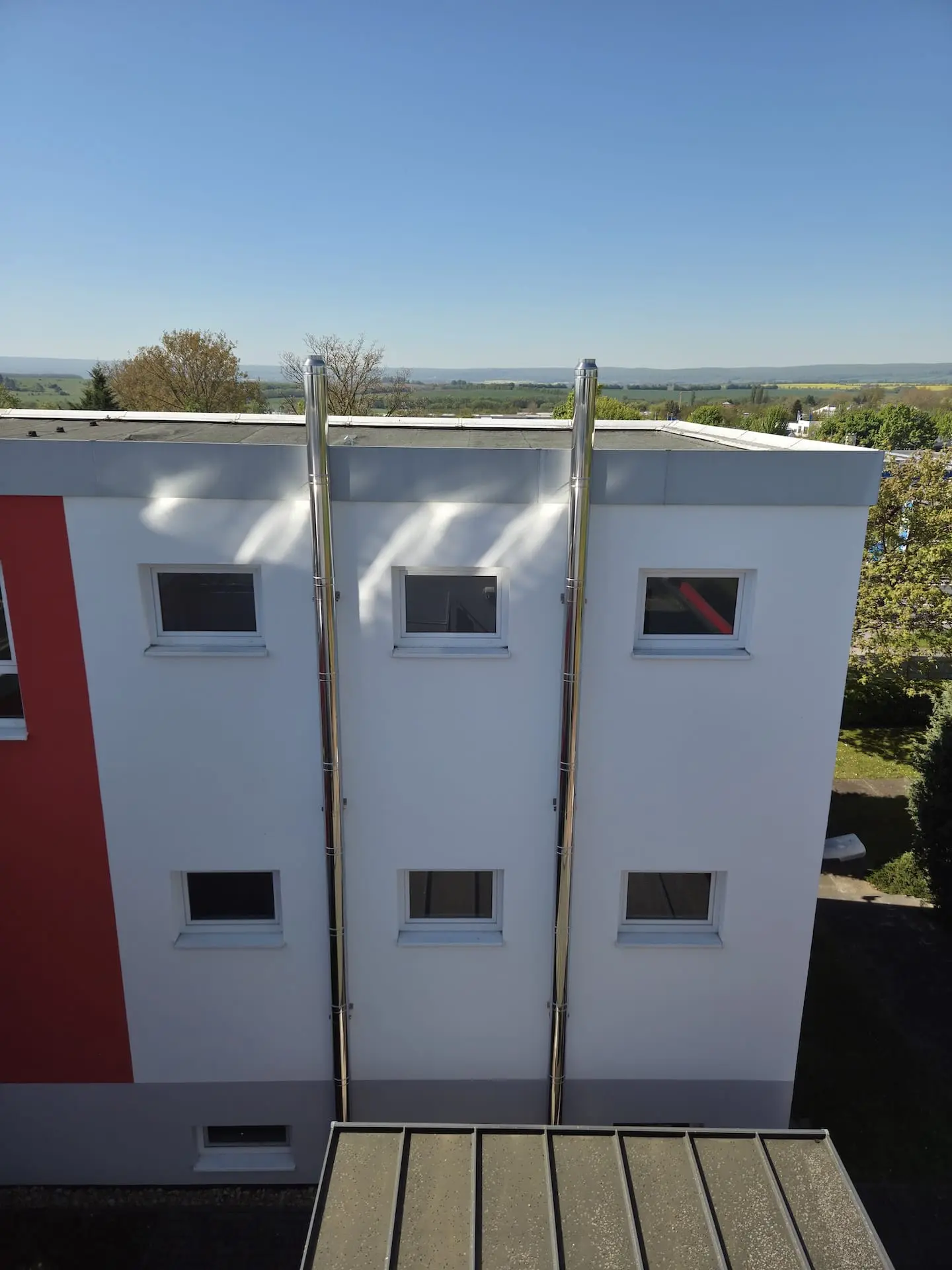 Zwei doppelwandige Edelstahlschornsteine an der Außenwand eines dreigeschossigen Wohnheims in Mühlhausen